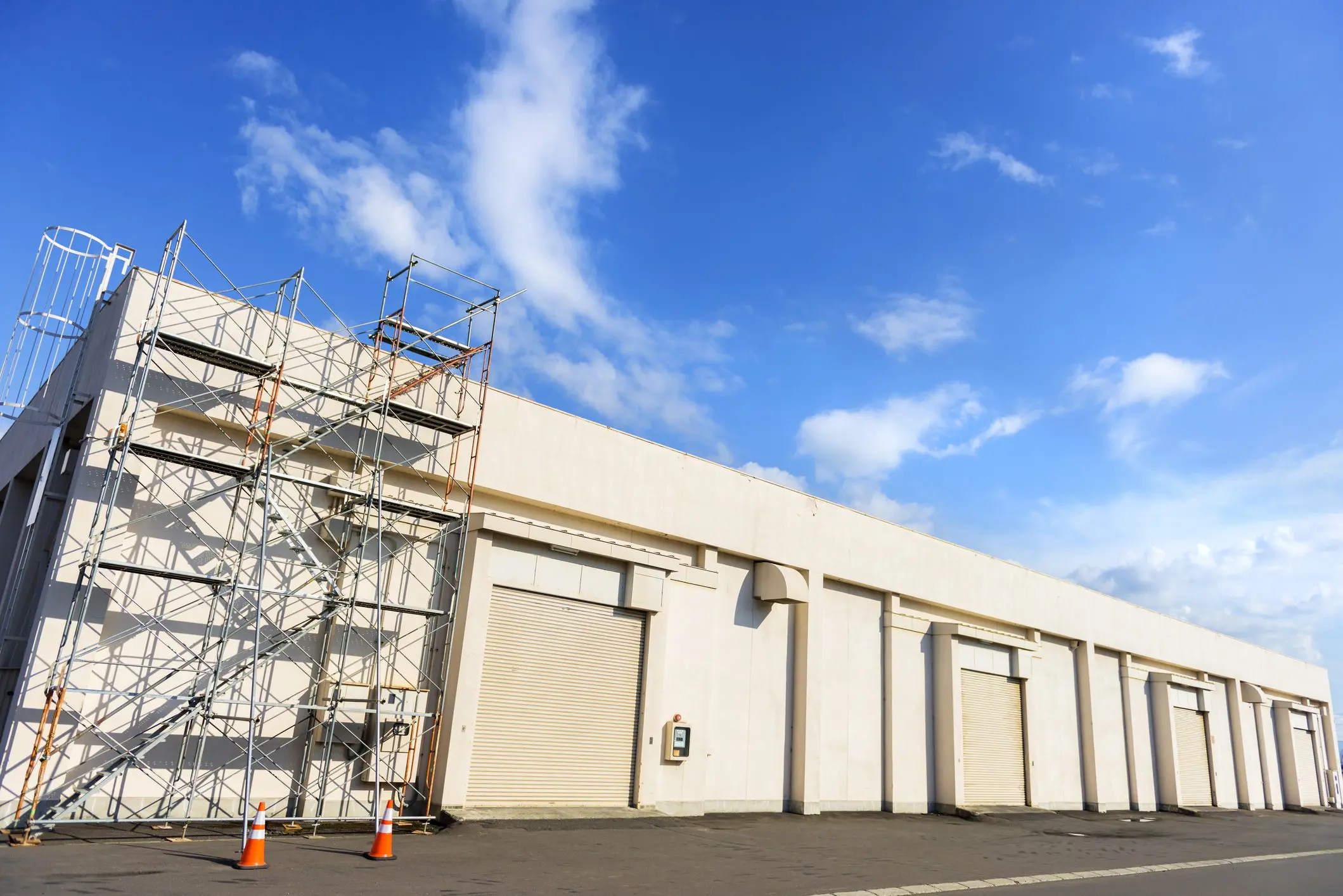Warehouse exterior with scaffolding and blue sky.
