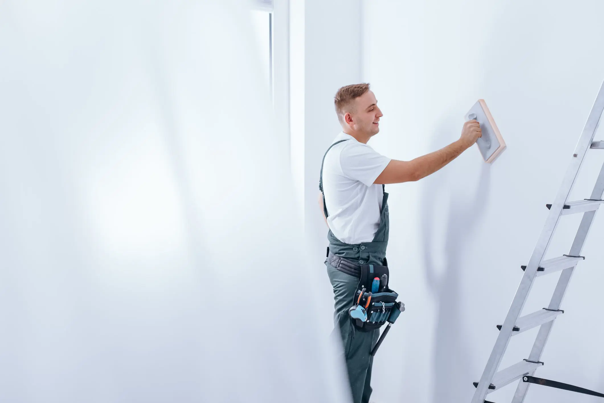 Painter smoothing white wall with tool