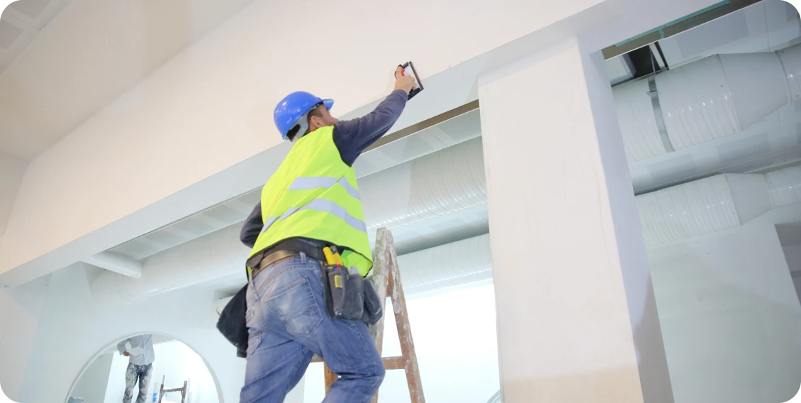 Construction worker painting high ceiling